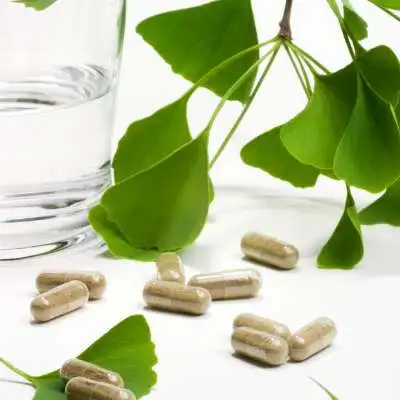 plante ginko biloba et gelule de plantes sur une table avec un verre d'eau